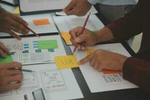 Close up ux developer and ui designer brainstorming about mobile app interface wireframe design on table with customer breif and color code at modern office.Creative digital development agency photo