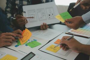 Close up ux developer and ui designer brainstorming about mobile app interface wireframe design on table with customer breif and color code at modern office.Creative digital development agency photo