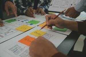 Close up ux developer and ui designer brainstorming about mobile app interface wireframe design on table with customer breif and color code at modern office.Creative digital development agency photo
