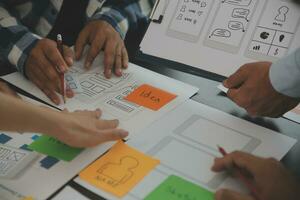 Close up ux developer and ui designer brainstorming about mobile app interface wireframe design on table with customer breif and color code at modern office.Creative digital development agency photo