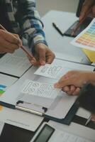 Close up ux developer and ui designer brainstorming about mobile app interface wireframe design on table with customer breif and color code at modern office.Creative digital development agency photo