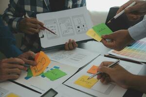 Close up ux developer and ui designer brainstorming about mobile app interface wireframe design on table with customer breif and color code at modern office.Creative digital development agency photo