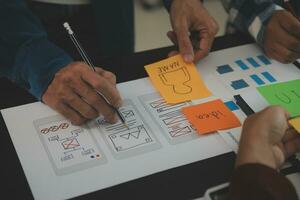 Close up ux developer and ui designer brainstorming about mobile app interface wireframe design on table with customer breif and color code at modern office.Creative digital development agency photo