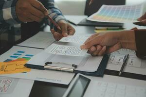 Close up ux developer and ui designer brainstorming about mobile app interface wireframe design on table with customer breif and color code at modern office.Creative digital development agency photo