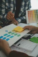 Close up ux developer and ui designer brainstorming about mobile app interface wireframe design on table with customer breif and color code at modern office.Creative digital development agency photo