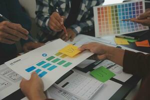 Close up ux developer and ui designer brainstorming about mobile app interface wireframe design on table with customer breif and color code at modern office.Creative digital development agency photo