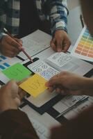 Close up ux developer and ui designer brainstorming about mobile app interface wireframe design on table with customer breif and color code at modern office.Creative digital development agency photo