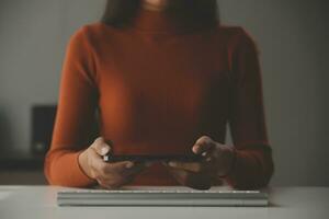 Asian Businesswoman Using laptop computer and working at office with calculator document on desk, doing planning analyzing the financial report, business plan investment, finance analysis concept. photo