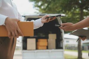 asiático mujer recepción producto desde entrega hombre a hogar, joven propietario mujer orden producto desde teléfono inteligente solicitud, mujer con en línea negocio o SME concepto. foto