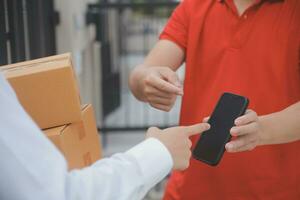 Asian Woman Receiving Product from delivery man at Home, Young Owner Woman Order Product from Smartphone Application, Woman with Online Business or SME Concept. photo