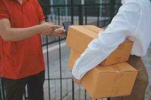 Asian Woman Receiving Product from delivery man at Home, Young Owner Woman Order Product from Smartphone Application, Woman with Online Business or SME Concept. photo