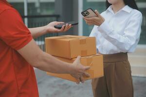 Asian Woman Receiving Product from delivery man at Home, Young Owner Woman Order Product from Smartphone Application, Woman with Online Business or SME Concept. photo