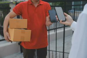 Asian Woman Receiving Product from delivery man at Home, Young Owner Woman Order Product from Smartphone Application, Woman with Online Business or SME Concept. photo