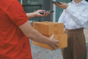 Asian Woman Receiving Product from delivery man at Home, Young Owner Woman Order Product from Smartphone Application, Woman with Online Business or SME Concept. photo