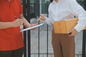 asiático mujer recepción producto desde entrega hombre a hogar, joven propietario mujer orden producto desde teléfono inteligente solicitud, mujer con en línea negocio o SME concepto. foto