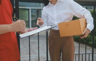 Asian Woman Receiving Product from delivery man at Home, Young Owner Woman Order Product from Smartphone Application, Woman with Online Business or SME Concept. photo