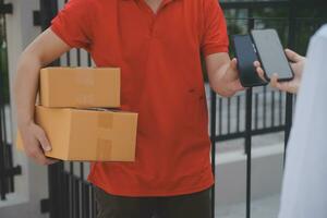 Asian Woman Receiving Product from delivery man at Home, Young Owner Woman Order Product from Smartphone Application, Woman with Online Business or SME Concept. photo
