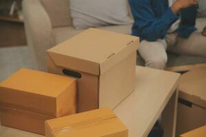 Beautiful young couple in love having fun unpacking things from cardboard boxes while moving in together in their new apartment photo