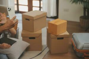 Beautiful young couple in love having fun unpacking things from cardboard boxes while moving in together in their new apartment photo