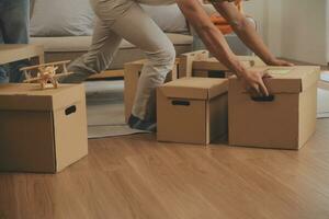 Beautiful young couple in love having fun unpacking things from cardboard boxes while moving in together in their new apartment photo