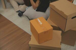 Beautiful young couple in love having fun unpacking things from cardboard boxes while moving in together in their new apartment photo