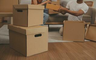 Beautiful young couple in love having fun unpacking things from cardboard boxes while moving in together in their new apartment photo