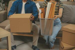 Beautiful young couple in love having fun unpacking things from cardboard boxes while moving in together in their new apartment photo