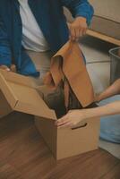 Beautiful young couple in love having fun unpacking things from cardboard boxes while moving in together in their new apartment photo