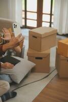 Beautiful young couple in love having fun unpacking things from cardboard boxes while moving in together in their new apartment photo