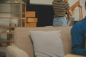 Beautiful young couple in love having fun unpacking things from cardboard boxes while moving in together in their new apartment photo