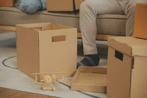 Beautiful young couple in love having fun unpacking things from cardboard boxes while moving in together in their new apartment photo