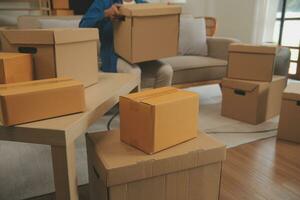 Beautiful young couple in love having fun unpacking things from cardboard boxes while moving in together in their new apartment photo