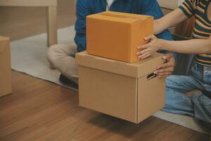 Beautiful young couple in love having fun unpacking things from cardboard boxes while moving in together in their new apartment photo