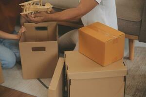 Beautiful young couple in love having fun unpacking things from cardboard boxes while moving in together in their new apartment photo