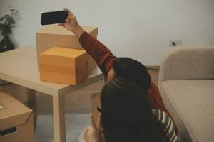 Beautiful young couple in love having fun unpacking things from cardboard boxes while moving in together in their new apartment photo