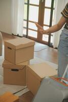 Beautiful young couple in love having fun unpacking things from cardboard boxes while moving in together in their new apartment photo