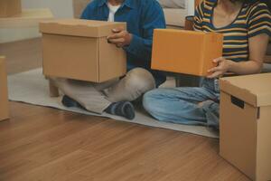 Beautiful young couple in love having fun unpacking things from cardboard boxes while moving in together in their new apartment photo