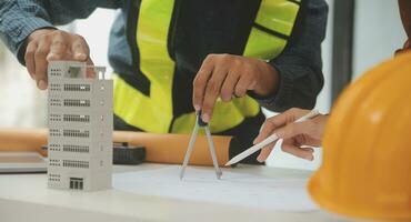 reunión de trabajo en equipo de ingenieros, trabajo de dibujo en la reunión de planos para el trabajo del proyecto con un socio en la construcción de modelos y herramientas de ingeniería en el concepto de sitio de trabajo, construcción y estructura. foto