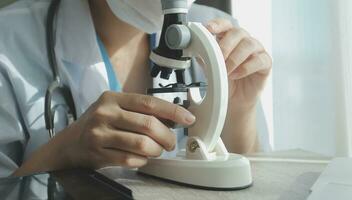 Young scientists conducting research investigations in a medical laboratory, a researcher in the foreground is using a microscope photo