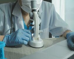 Young scientists conducting research investigations in a medical laboratory, a researcher in the foreground is using a microscope photo