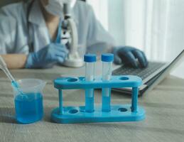 Young scientists conducting research investigations in a medical laboratory, a researcher in the foreground is using a microscope photo