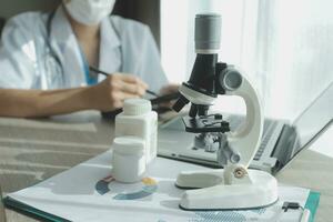Young scientists conducting research investigations in a medical laboratory, a researcher in the foreground is using a microscope photo