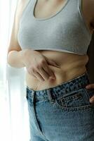 Close up of a belly with scar from c-section and abdominal fat. Women's health. A woman dressed up in sportswear demonstrating her imperfect body after a childbirth with nursery on the background. photo