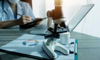 Young scientists conducting research investigations in a medical laboratory, a researcher in the foreground is using a microscope photo