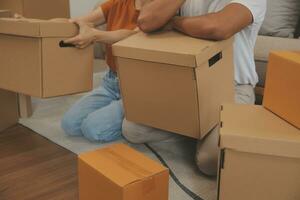 Beautiful young couple in love having fun unpacking things from cardboard boxes while moving in together in their new apartment photo