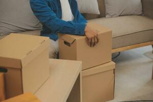 Beautiful young couple in love having fun unpacking things from cardboard boxes while moving in together in their new apartment photo