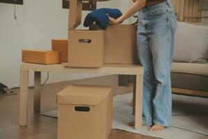 Beautiful young couple in love having fun unpacking things from cardboard boxes while moving in together in their new apartment photo