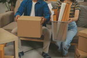 Beautiful young couple in love having fun unpacking things from cardboard boxes while moving in together in their new apartment photo