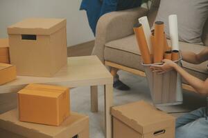 Beautiful young couple in love having fun unpacking things from cardboard boxes while moving in together in their new apartment photo