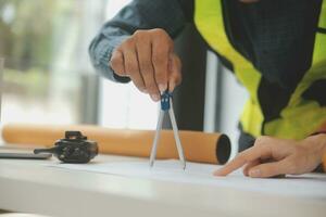 reunión de trabajo en equipo de ingenieros, trabajo de dibujo en la reunión de planos para el trabajo del proyecto con un socio en la construcción de modelos y herramientas de ingeniería en el concepto de sitio de trabajo, construcción y estructura. foto